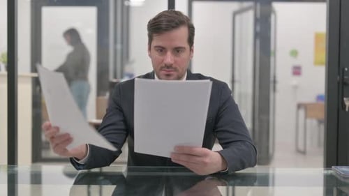 Mature Businessman Reading Documents in Office