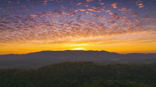 Beautiful of morning orange gold sky cloudscape over fertile forest mountains.