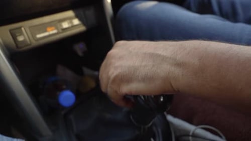 Close-up of male hand changing gear while driving an electric car