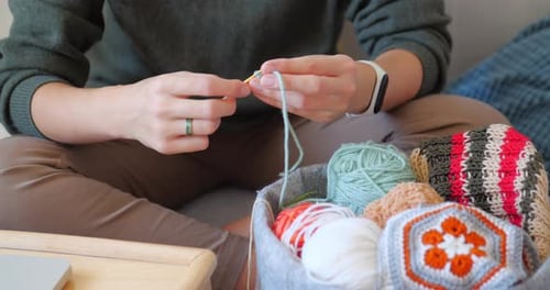 Hands Crocheting with Yarn in a Cozy Setting