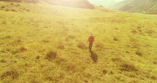 Flight Over Backpack Hiking Tourist Walking Across Green Mountain Field Huge Rural Valley at Summer