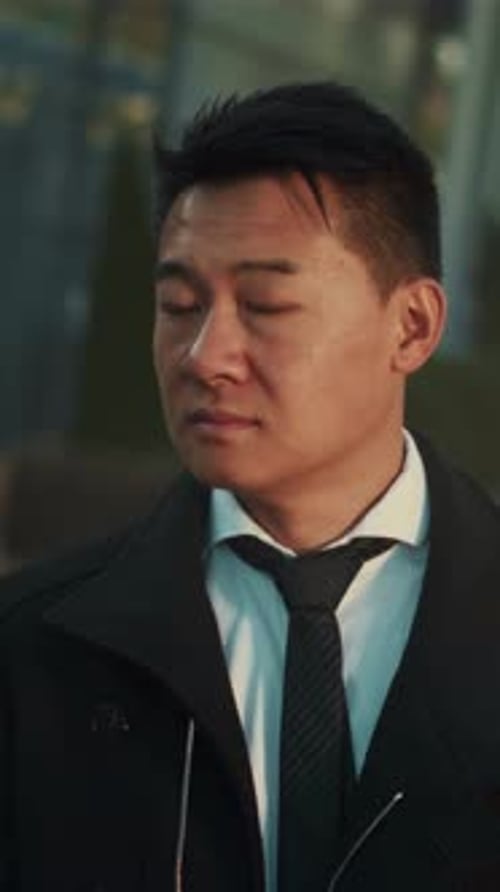 Evening Urban Scene Captures Thoughtful Businessman Gazing Into Reflective Surfaces with Gentle