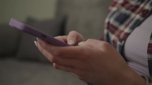 Young Woman Using Smartphone on Couch at Home