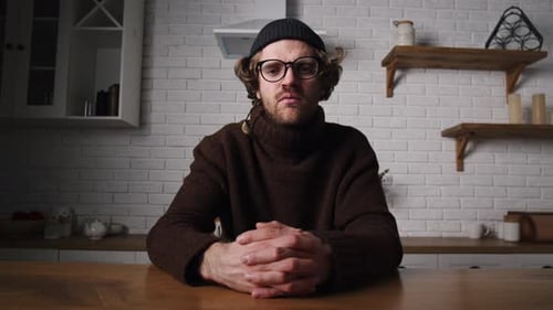 Man Sitting at Table Talking to Camera