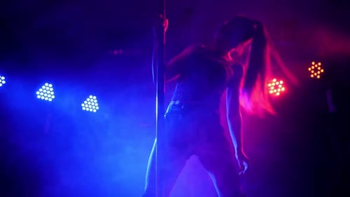 Silhueta de uma jovem esbelta em lingerie em uma boate perto de um poste