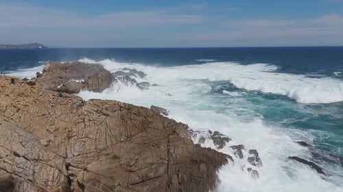 Dynamic aerial view capturing powerful waves crashing against rocks at Playa Chica in Quintay, showc