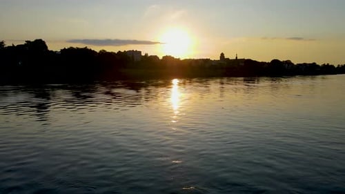 Sunset on Vistula in Poland River with Sky and Sunbeams Reflection in Water Trees Row Growing Along