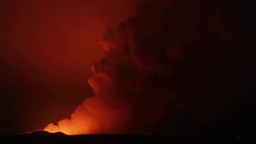 Große Rauchwolke, die durch einen Vulkanausbruch aufsteigt, mit orangefarbenem Schimmer der Lava