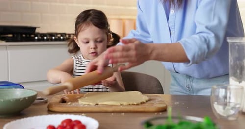 Child Helps Adult Roll Dough in Kitchen