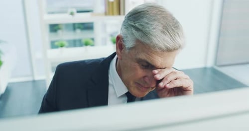 Tired Businessman Rubbing Eyes in Office Environment