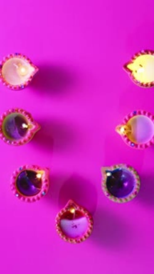 Vidéo verticale de bougies allumées en rang célébrant Diwali sur fond rose, avec espace de copie