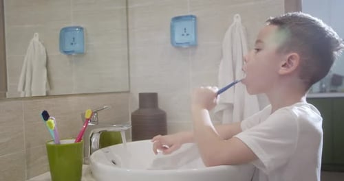 Young Child Brushing Teeth in Bathroom Sink