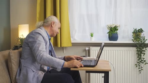 Adult Man Uses Laptop at Home, Smiling
