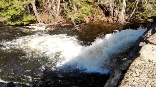 Handheld clip of water flowing down the dam in slow motion on a sunny day.
