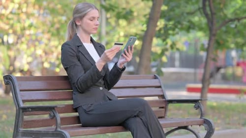 Woman Uses Smartphone and Credit Card on Bench