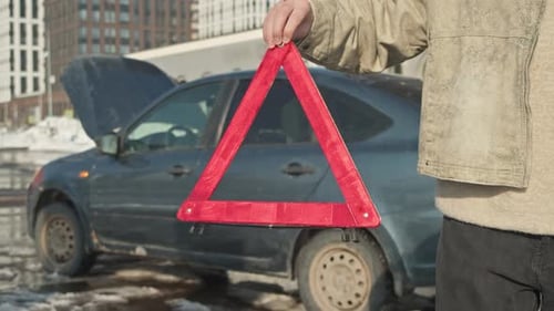 Winter Car Breakdown Emergency Triangle in Foreground Blue Car with Open Hood in Background