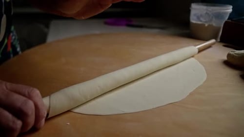 Pastry Professional Smoothly Rolling Delicate Dough Onto Wooden Pin Revealing Precise Culinary