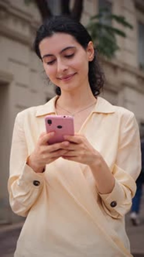 Young Woman Engaged in Smartphone Communication While Enjoying a Pleasant Day Outdoors in the City