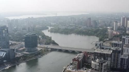 Aerial view of a wide beautiful river flowing along the green parks and city streets