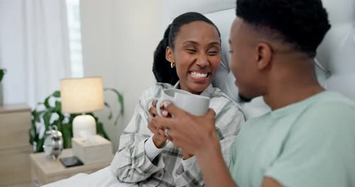 Young Couple Laughing and Drinking Coffee in Bed