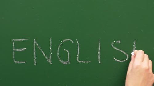 A Hand Writes English On A Green Chalkboard
