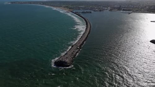 Vista aérea de um longo quebra-mar que se estende até o oceano