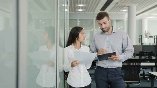 Business Young Man and Woman Colleagues Stand in Office Communicate Discuss Joint Project Girl