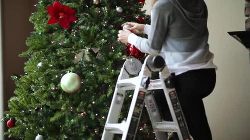 Woman decorating Christmas Tree at Home