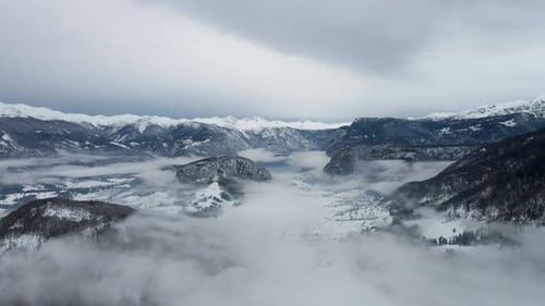 Cloud mist surfing aerial winter mountain range peaks snow fog day