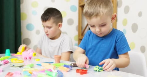 Two Young Boys Play with Colorful Plasticine Indoors