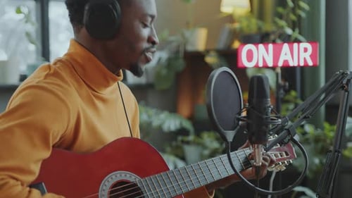 Musiker singt und spielt Gitarre während der Radiosendung im Rundfunkstudio