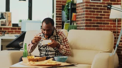 Man Eating Noodles in Urban Apartment