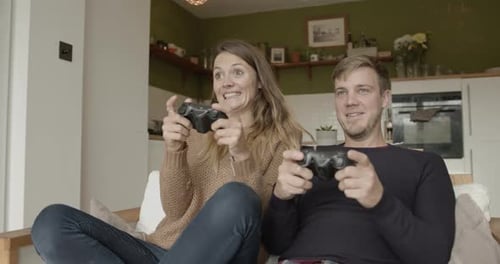 Couple Playing Video Games Together at Home on Couch