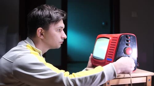 a Man Turns the Channel Knob on an Old Tube TV Young Man Engaging with Retro Television Set