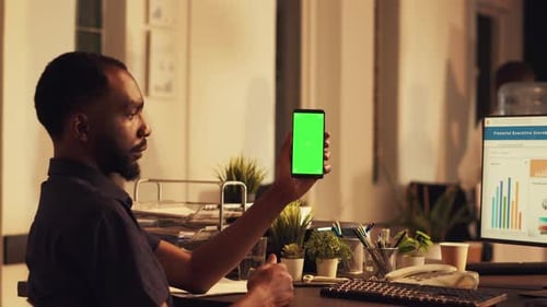 Man Holds Smartphone with Green Screen in Office