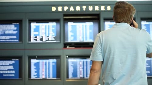 Man at Airport in Front of Departure Screens Adult