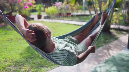 Woman is resting in hammock and enjoying summer in garden