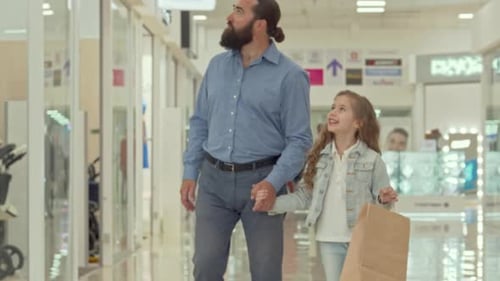 Joyful Father and His Charming Daughter Exploring a Vibrant Shopping Mall