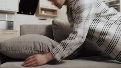 Tired Young Caucasian Man Falling Face Down Into a Pillow on a Couch at Home After a Hard Work Day