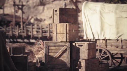 Wooden Crates Stacked Beside a Covered Wagon in an Old Western Town