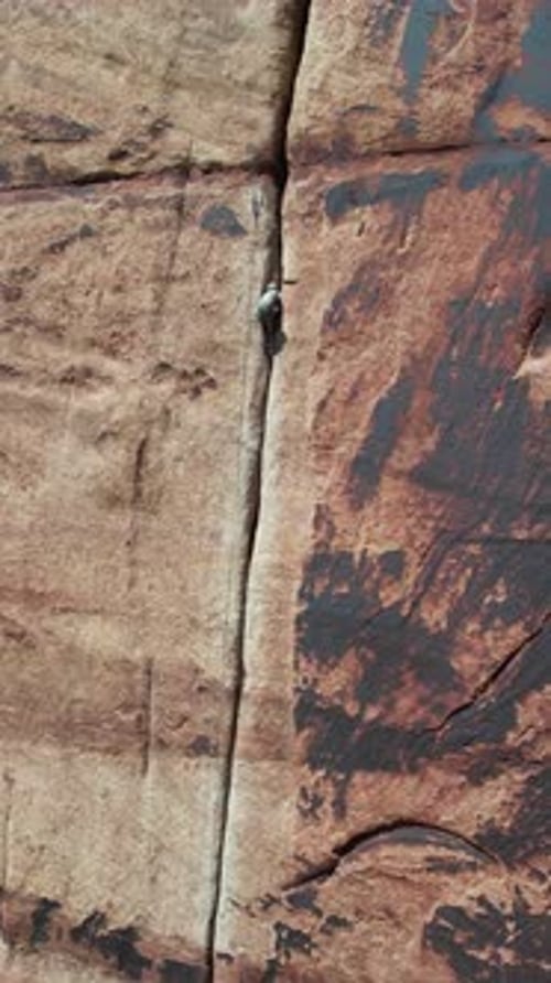 Vertical Aerial View of Climber, Ropes and Crack in Steep Sandstone Cliff, Extreme Sport Drone Shot