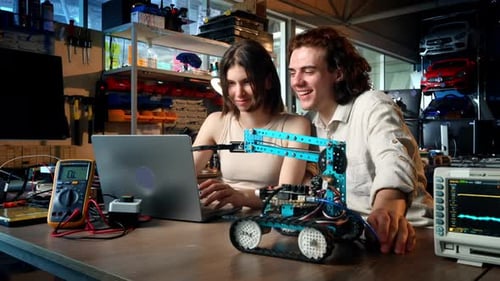 Junger Mann und Frau machen Experimente in Robotik in einem Labor mit einem Computer. Roboter und Werkzeuge