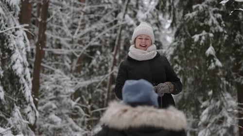 Mother Rolls Child on Sled in Snowy Forest Dancing with Her Son