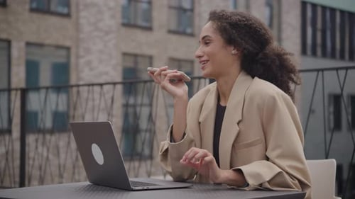 Young Woman Using Phone and Laptop Outdoors