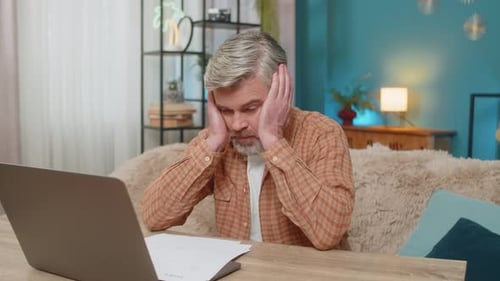 Frustrated Man Reviews Documents at Home Office
