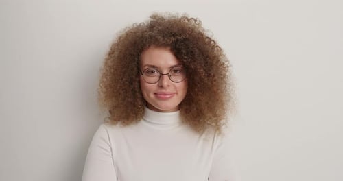 Smiling young woman with curly hair and glasses