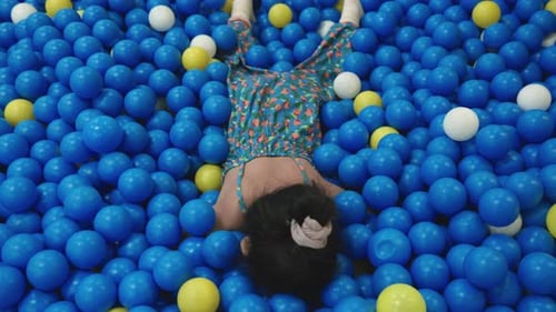 Happy Asian child woman having fun on entertainment center inflatable castle in balls sea