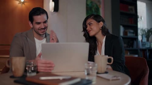 Latin Business Professionals Discussing Content on Laptop in Modern Cafe