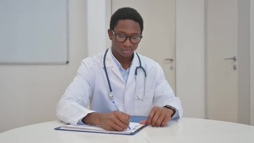 Young Doctor Writing on Chart in Exam Room