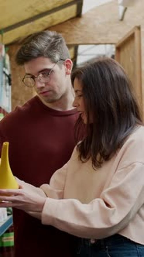 Happy Brunette Girl and Her Boyfriend Choose a Watering Can in a Garden Care Store